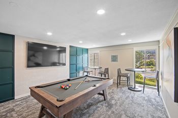 A pool table is in the middle of a room with a chair and a small table at Delphine on Diamond, San Francisco, 94131